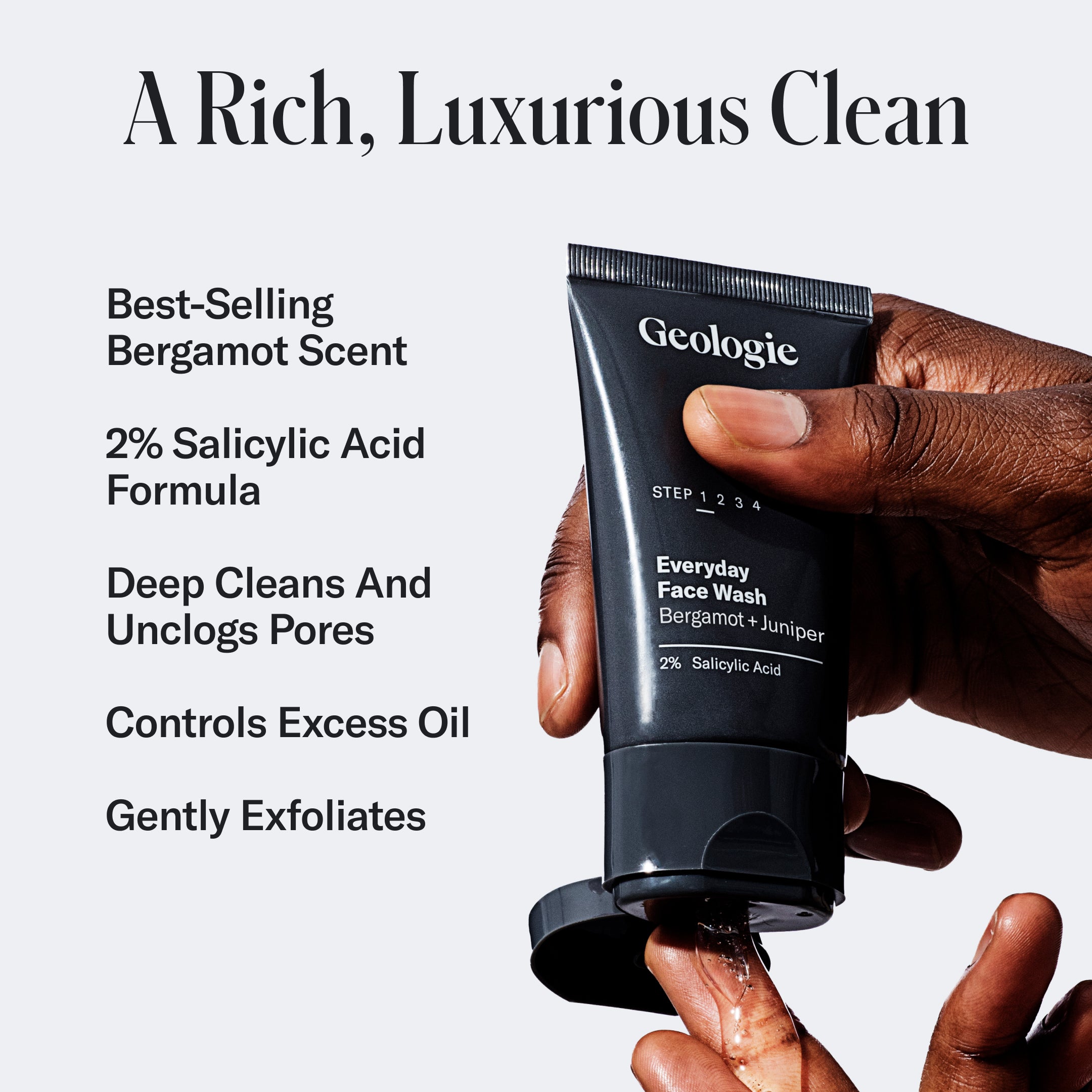 A hand holding a tube of Geologie Deluxe Skincare Set with text describing it as a luxurious, best-selling 2% salicylic acid formula that exfoliates and controls oil, preventing breakouts.